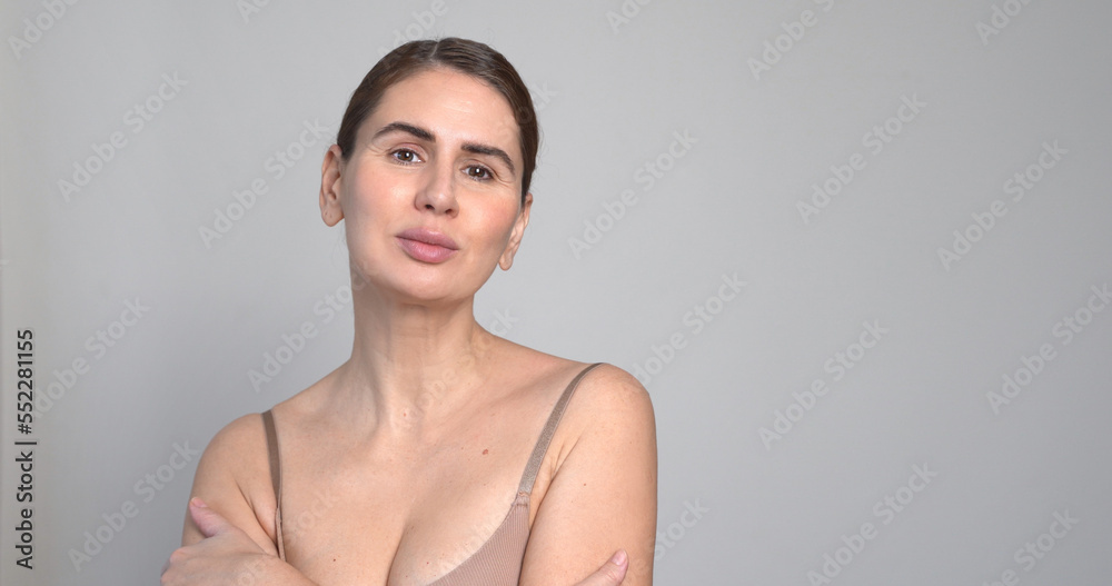 Obraz premium Middle Aged Woman White Background. Female 40 Year Lady Looking At Camera Smiling. Concept of Enjoying Her natural beauty, High Self Esteem, Wellness. Natural Cosmetic Skincare Products.