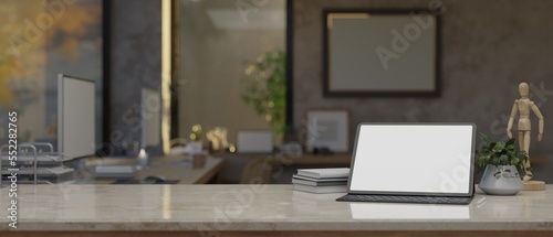 Modern office desk with tablet mockup, decor and copy space over blurred modern office