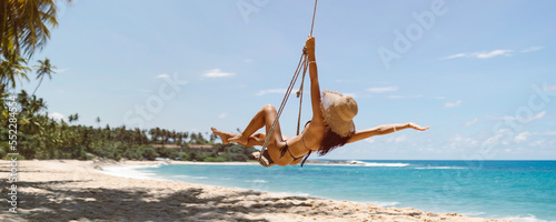 Bikini Beach Girl Model in Black Swimsuit on Palm Tree Swing on photo
