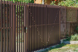 Brown metal fence with brick posts. Metal fencing of private property in the countryside. Security concept
