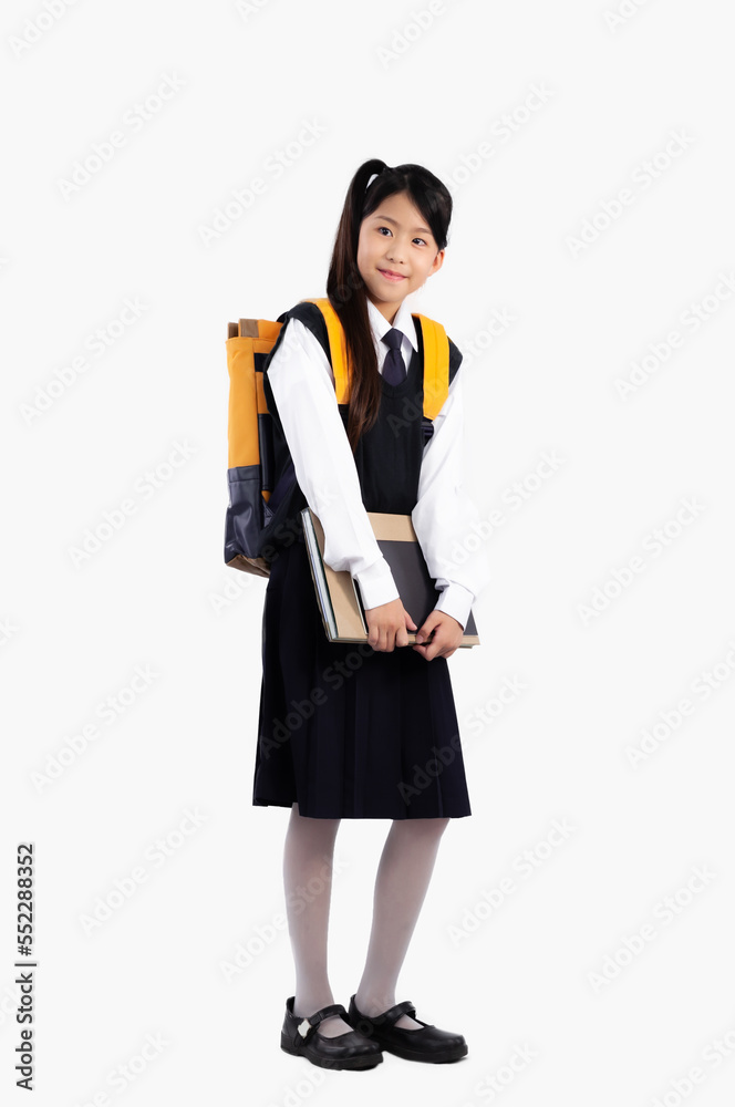 Asian girl school student in british international uniform carrying backpack and book posing full length on white background.