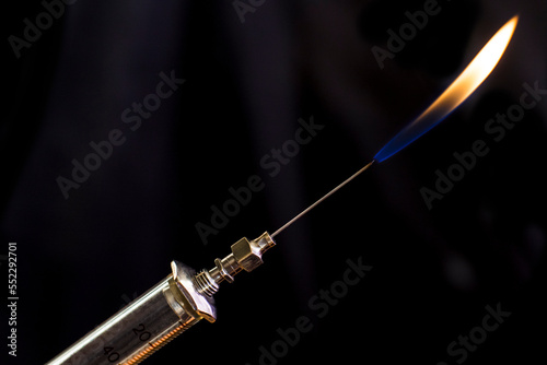A gas torch from metal needle on a retro glass syringe