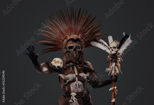 Shot of female shaman from past dressed in ceremonial attire holding staff.