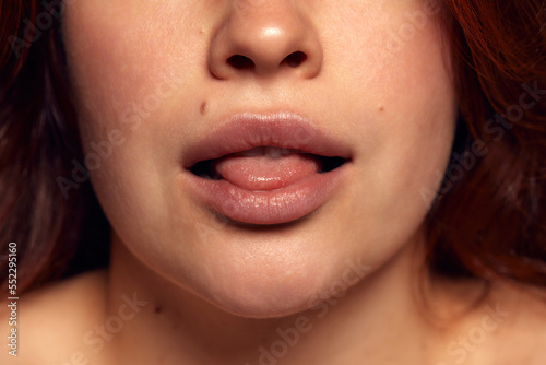Close-up view of female perfect shape mouth with nude colored lipstick. Moisturizing care. Cosmetological lip fillers