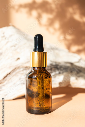 Amber glass dropper bottle on a natural wood background. Side view, space for text. The concept of natural, organic cosmetics. Vertical image.