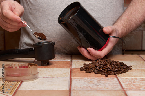 Preparation of coffee: male hands pour ground coffee into the horn of the coffee maker