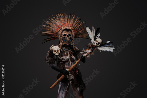 Studio shot of creepy aztec witch dressed in aboriginal attire with plumed headdress.