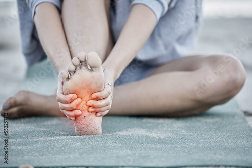 Foot, injury and pain with a woman holding her sole during fitness exercise with digital CGI or overlay. Workout, training and beach with a female athlete suffering from a sore joint or bone photo