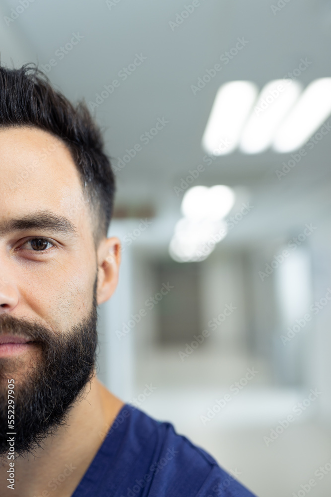 Obraz premium Vertical half portrait of bearded caucasian male healthcare worker in hospital corridor, copy space