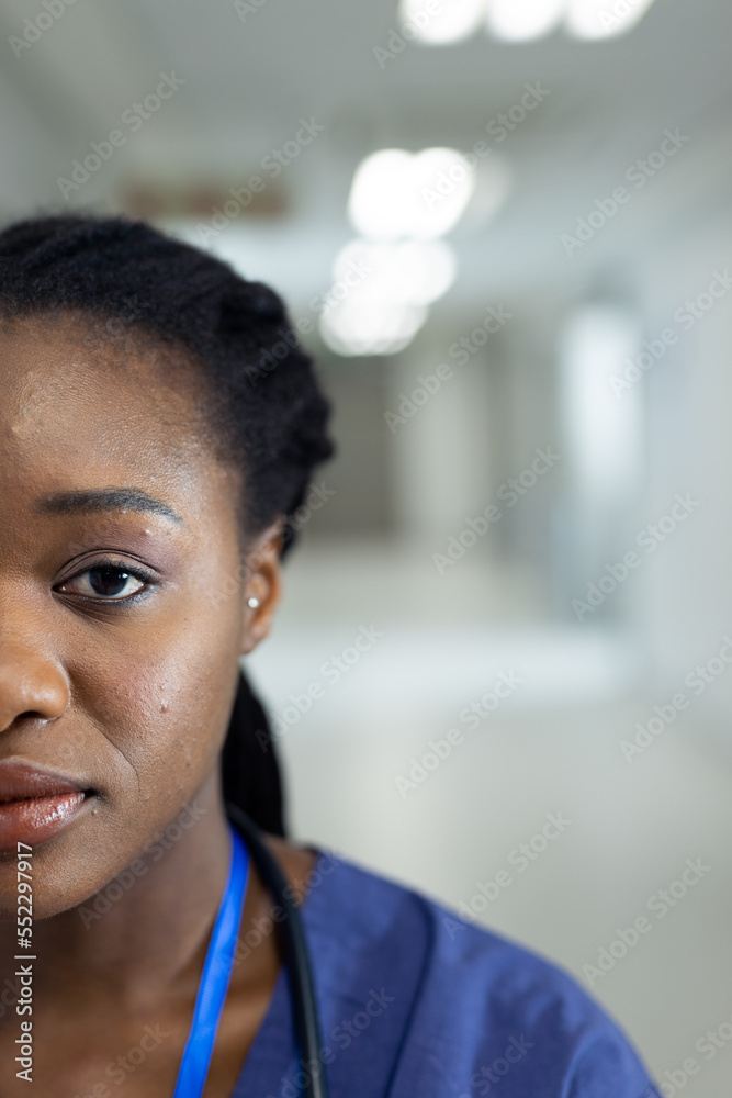 Vertical half face portrait of african american female doctor in hospital corridor, copy space Vertical half face portrait of african american female doctor in hospital corridor, copy space