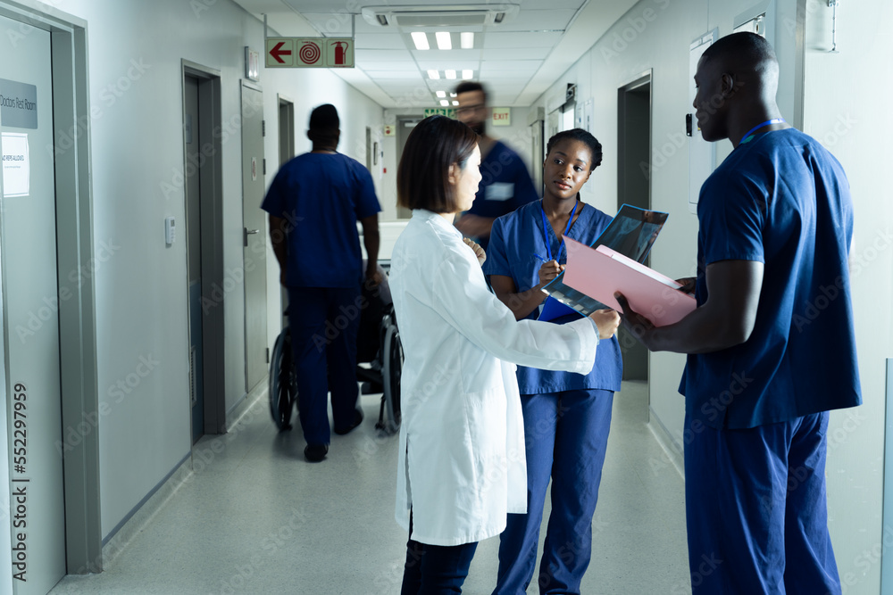 Diverse female doctor and healthcare workers discussing in hospital corridor, copy space Diverse female doctor and healthcare workers discussing in hospital corridor, copy space