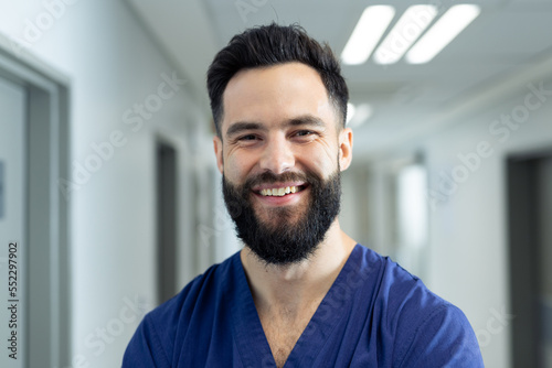 Portrait of smiling bearded caucasian male healthcare worker in hospital corridor, copy space
