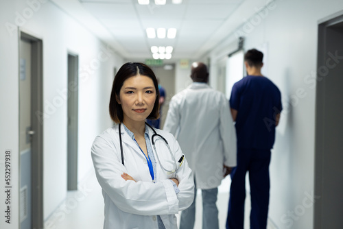 Portrait of smiling asian female doctor in busy hospital corridor, copy space