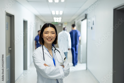Portrait of smiling asian female doctor in busy hospital corridor, copy space