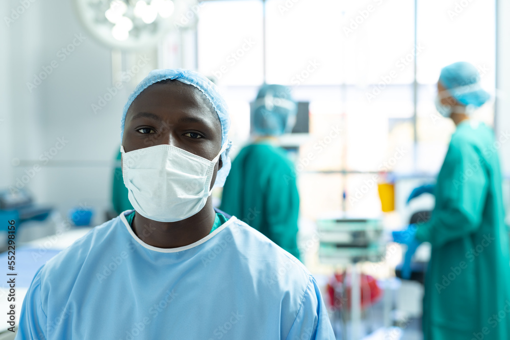 Portrait of african american male surgeon wearing face mask in operating theatre, with copy space Portrait of african american male surgeon wearing face mask in operating theatre, with copy space
