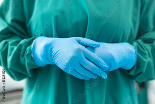 Midsection of female surgeon ready for operation in blue surgical gloves and green gown