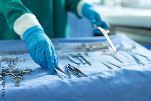 Midsection of surgical tech placing surgical tools on table in operating theatre