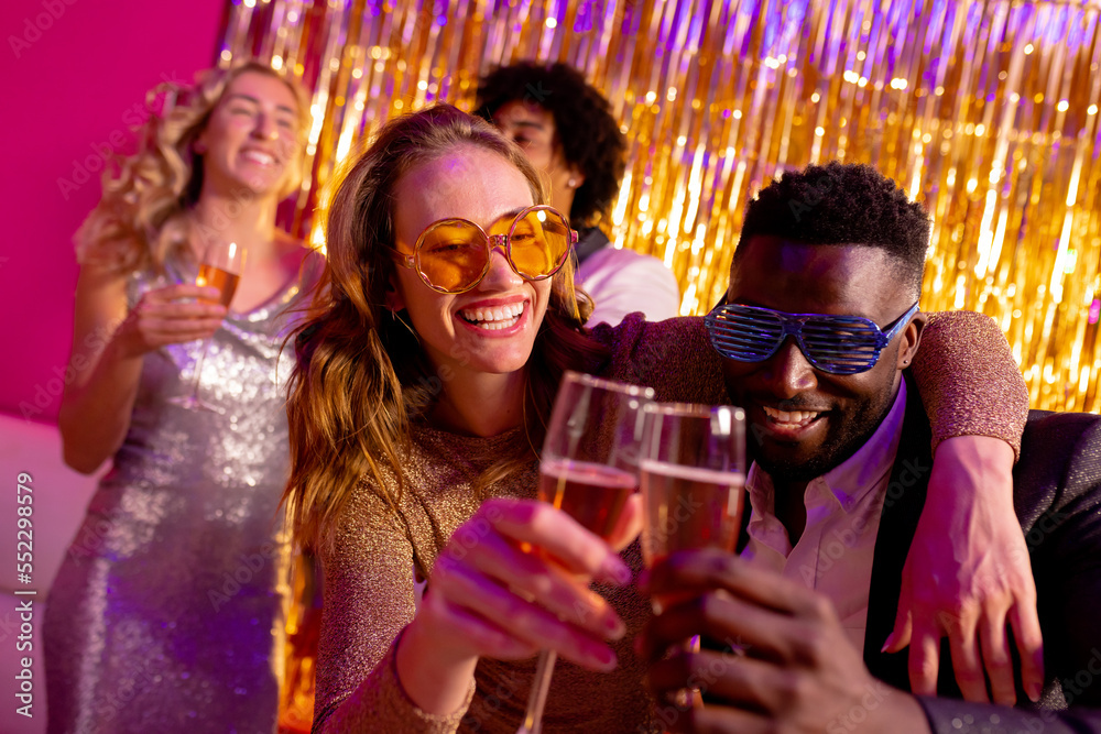 Happy diverse couple dancing and toasting with champagne at a nightclub