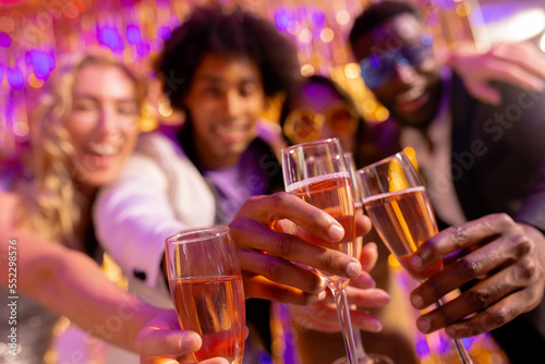 Selective focus of four happy, diverse friends toasting with glasses of champagne at a nightclub