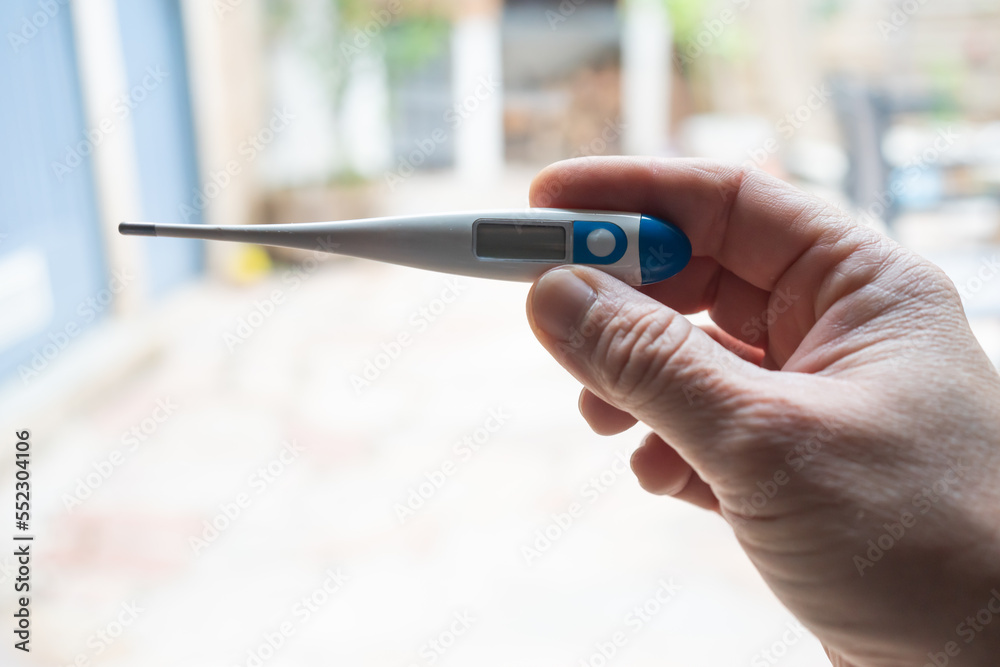 Illness. Home treatment. Flu and cold. A man takes his temperature with a thermometer
