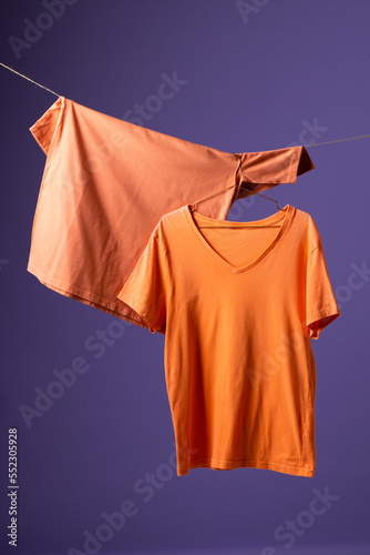 Tshirts hanging on coat hanger and copy space on purple background