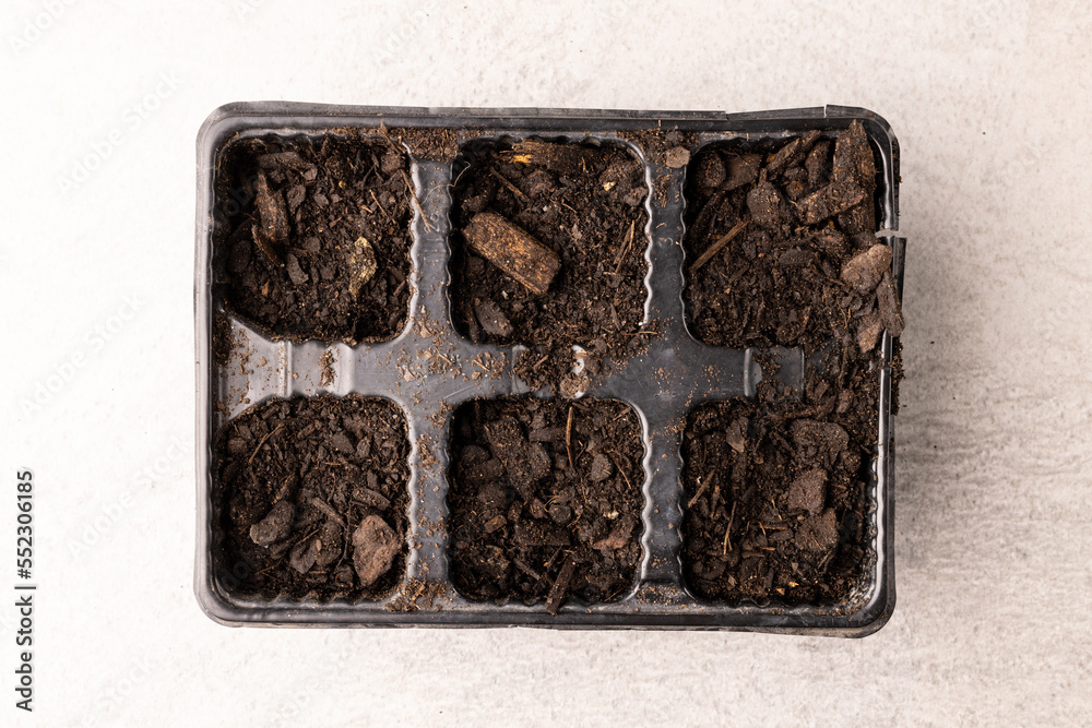 Overhead view of seedling tray filled with dark soil and bark pieces Overhead view of seedling tray filled with dark soil and bark pieces