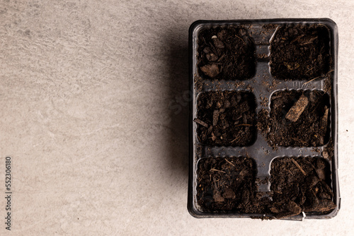 Overhead of seedling tray filled with dark soil with bark pieces, with copy space