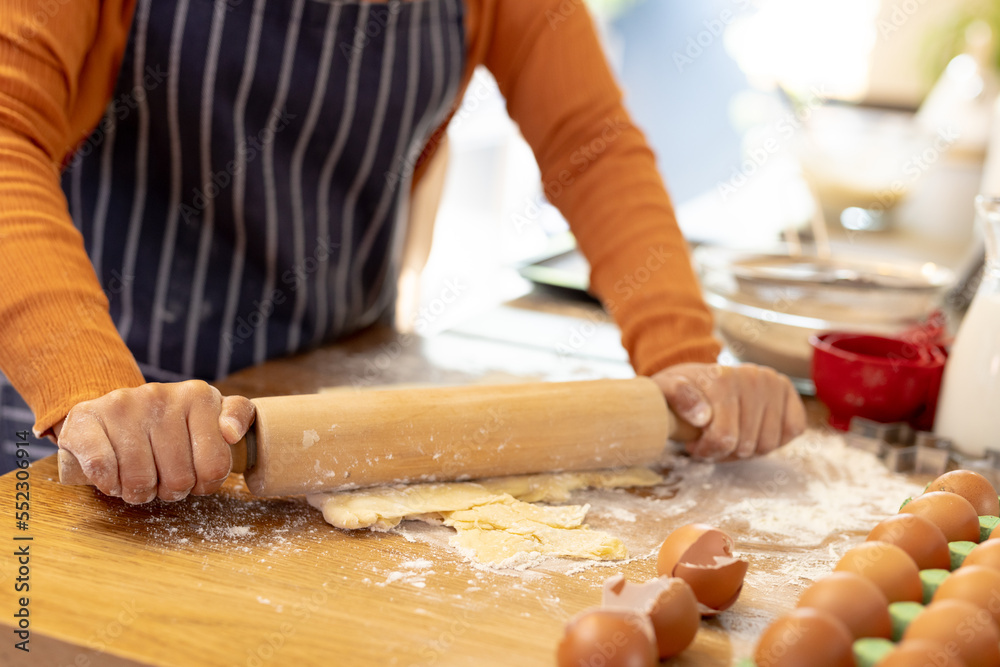 Midsection of biracial woman wearing hijab, standing in kitchen and baking Midsection of biracial woman wearing hijab, standing in kitchen and baking