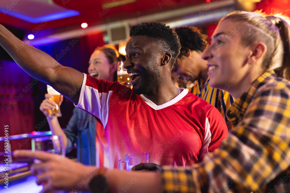 Diverse group of excited male and female friends watching sports game showing at a bar Diverse group of excited male and female friends watching sports game showing at a bar