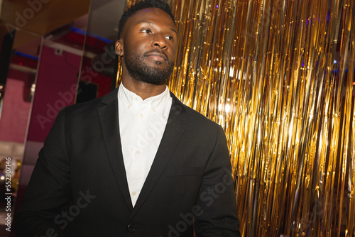 Smartly dressed, serious african american doorman at a nightclub looking away photo