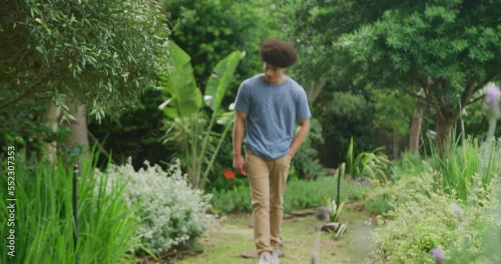 Happy biracial man walking in garden on sunny day Happy biracial man walking in garden on sunny day