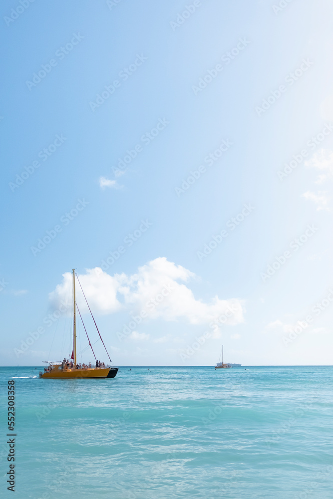 Catamaran boat on a clear sunny day sailing on the crystal clear blue ocean waves off the coast of Honolulu Hawaii