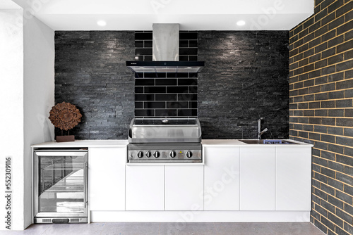 Outdoor white kitchen with barbecue, drink fridge and sink