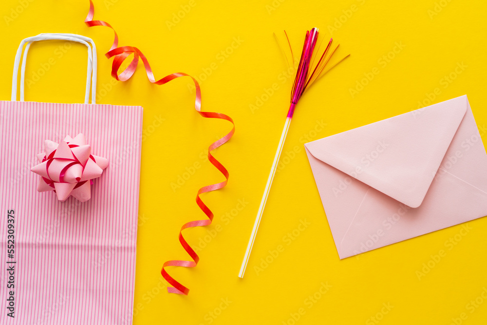 Top view of shopping bag near serpentine and envelope on yellow background. Top view of shopping bag near serpentine and envelope on yellow background.