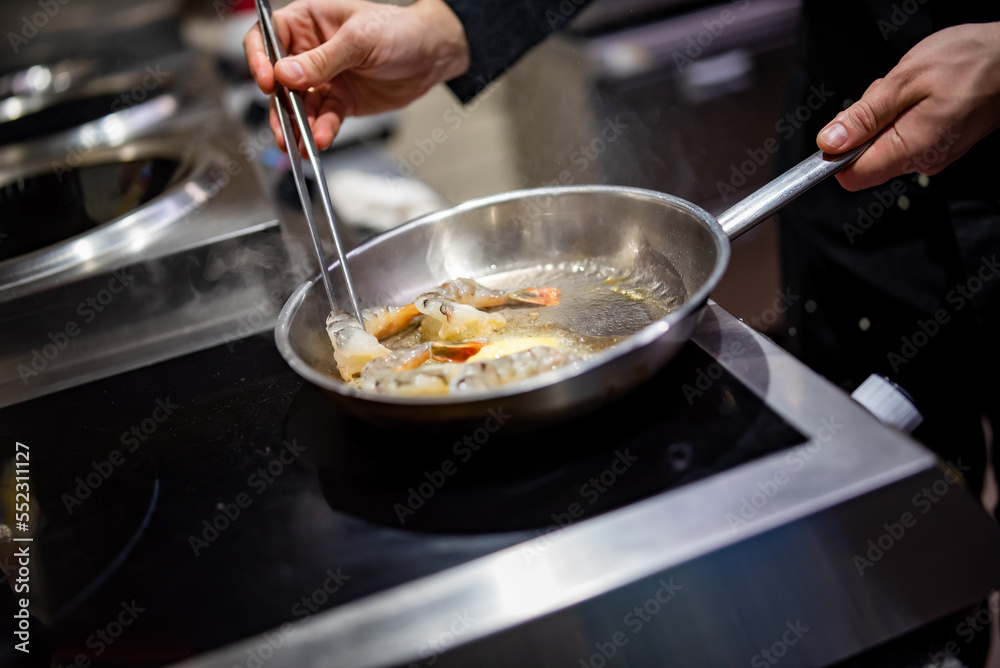 man chef cooking tasty shrimp in frying pan on kitchen man chef cooking tasty shrimp in frying pan on kitchen