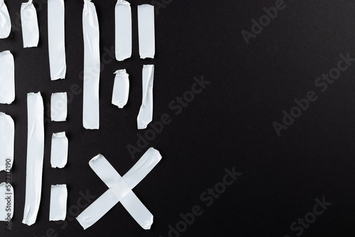 Ripped up pieces of white tape with copy space on black background