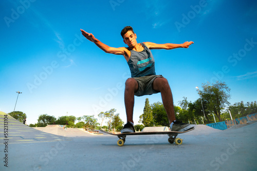 A young skateboarder doing tricks on skateboard at a park on a sunny day