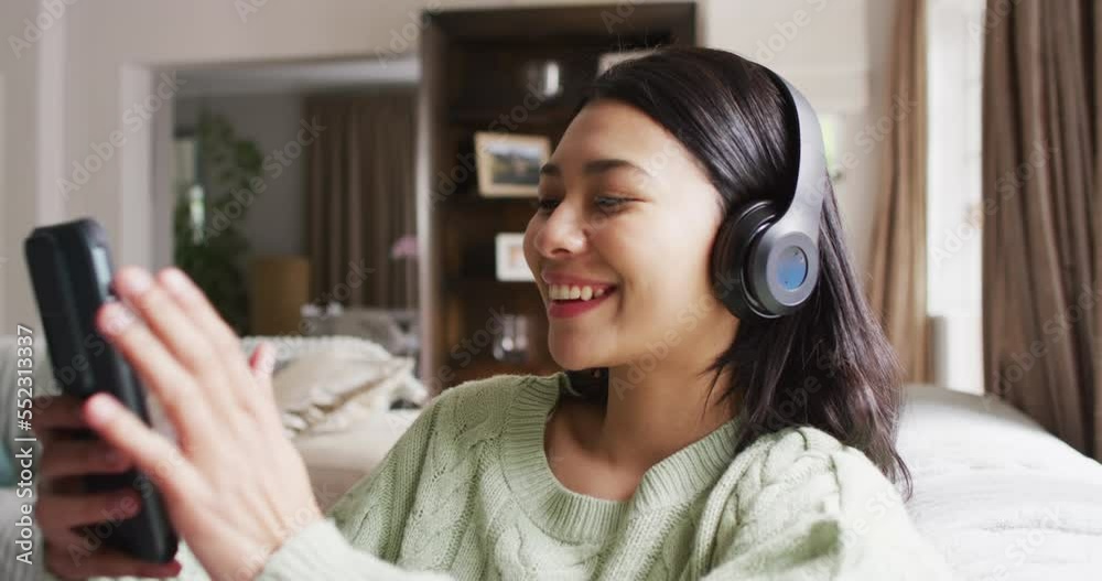 Video of smiling biracial woman with dark hair using headphones and smartphone Video of smiling biracial woman with dark hair using headphones and smartphone