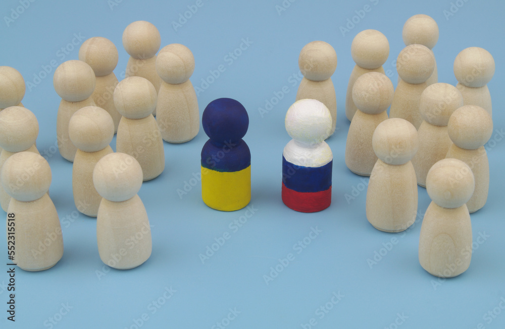 Obraz premium Wooden people figures are divided into two parts, and leaders is painted in colors of Ukrainian and Russian flags.