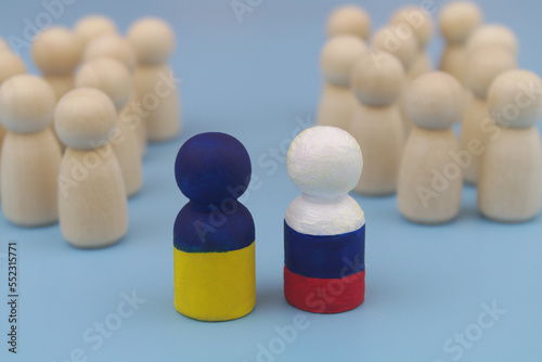 Wooden people figures are divided into two parts, and leaders is painted in colors of Ukrainian and Russian flags. Agreement between Russia and Ukraine, stopping hostilities and making peace concept.