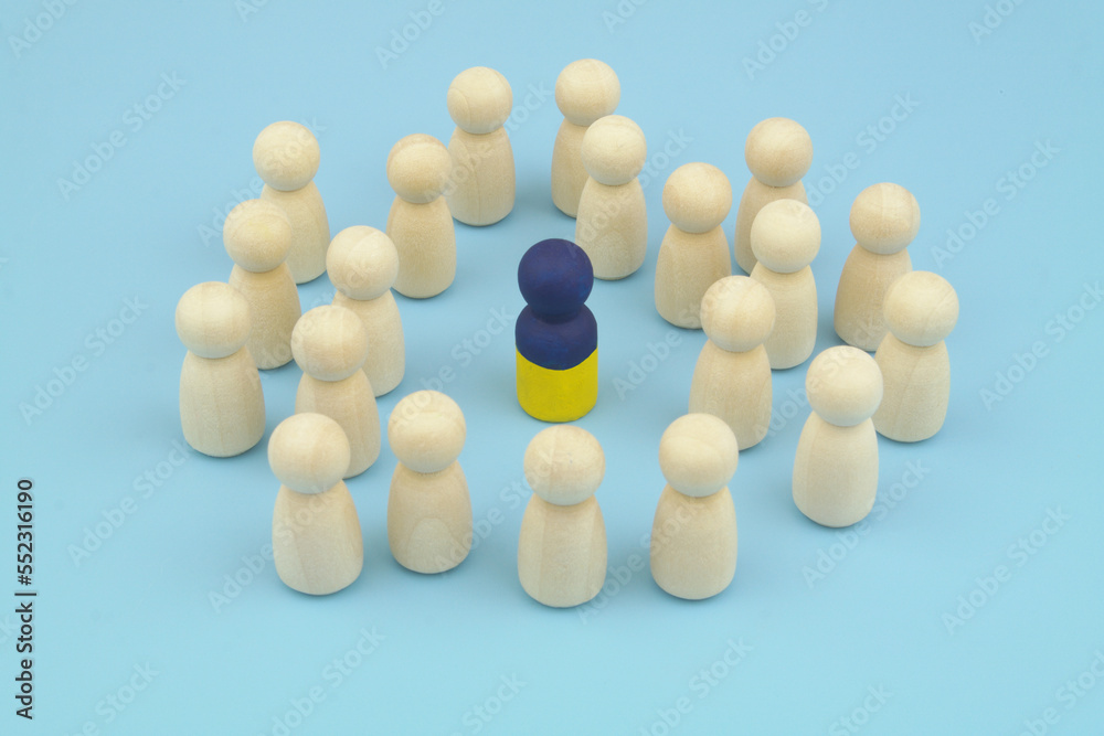 One leader with colors of Ukrainian flag and wooden people figures on blue background, One leader with colors of Ukrainian flag and wooden people figures on blue background,
