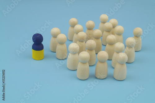 One leader with colors of Ukrainian flag and wooden people figures on blue background, © Valerii Evlakhov