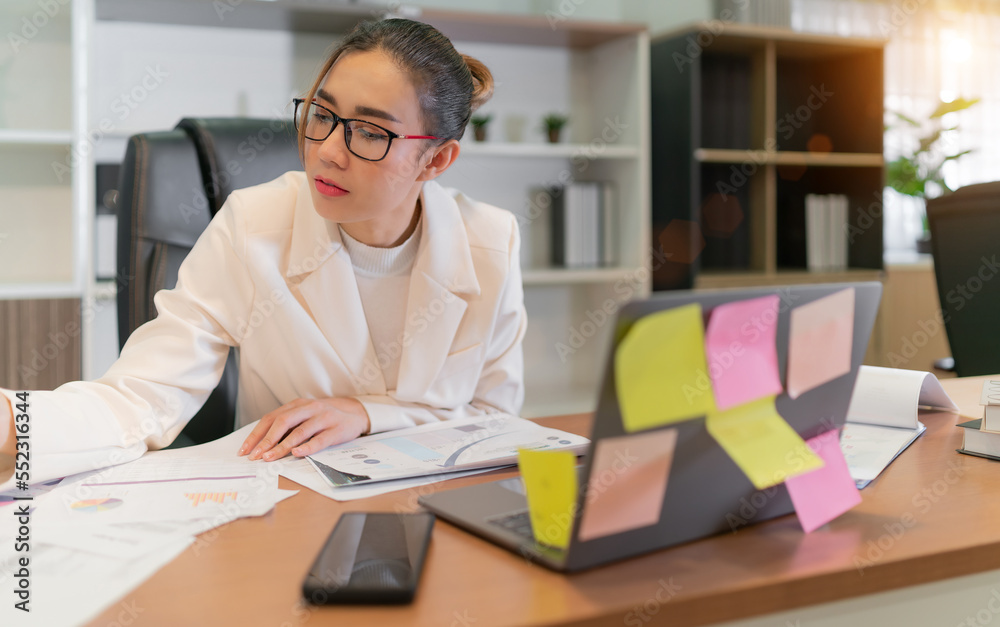 Business Asian woman manage accounting work. glasses female worker busy with online account group meetings and use laptop computer. Professional confident employee having team video call at workplace