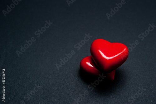 two red hearts shapes on a black background with copy space