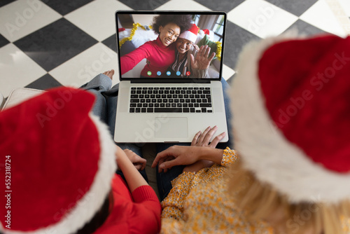 Caucasian mother and daughter having christmas video call with diverse people