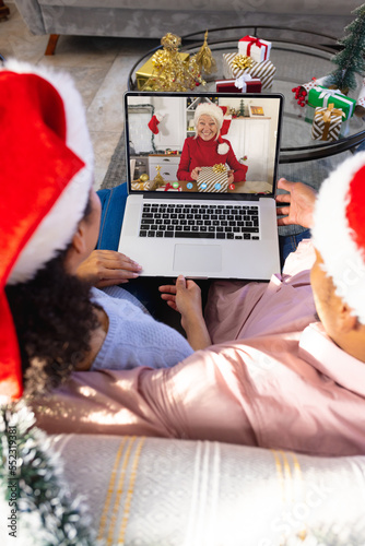 Biracial couple with christmas decorations having video call with happy caucasian woman