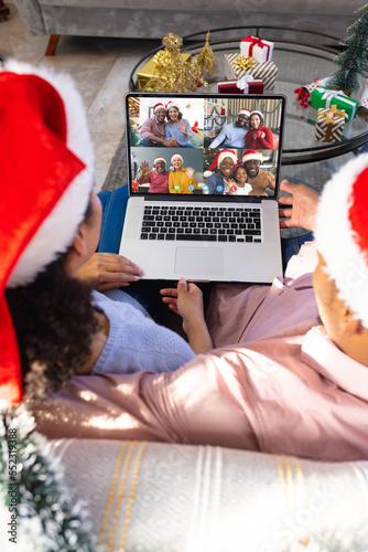 Biracial couple with christmas decorations having video call with happy diverse friends