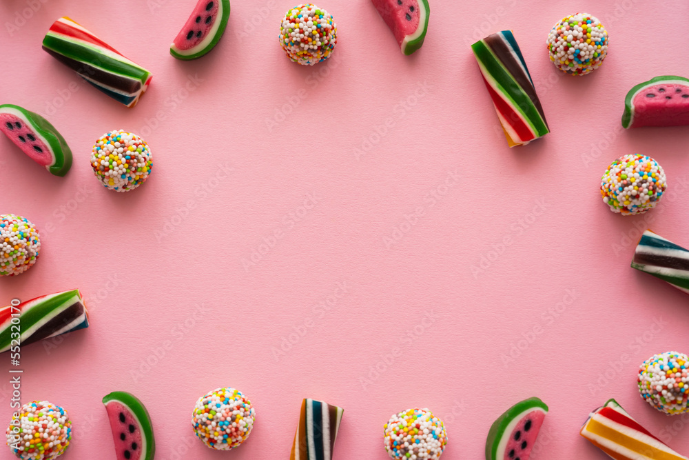 Top view of frame from colorful candies on pink background.