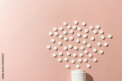 Composition of white pill box and white pills on pink background with copy space