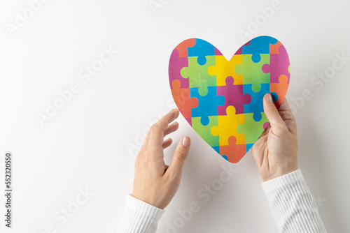 Composition of hands holding jigsaw puzzle heart on white background with copy space